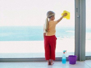 Девочка моет окно в квартире